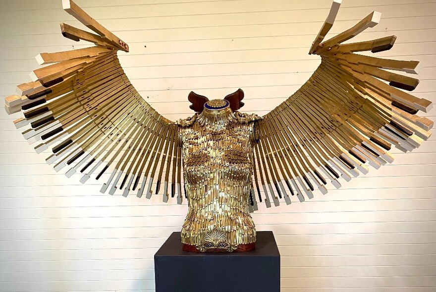 Large metal bird sculpture on a plinth, with open wings.