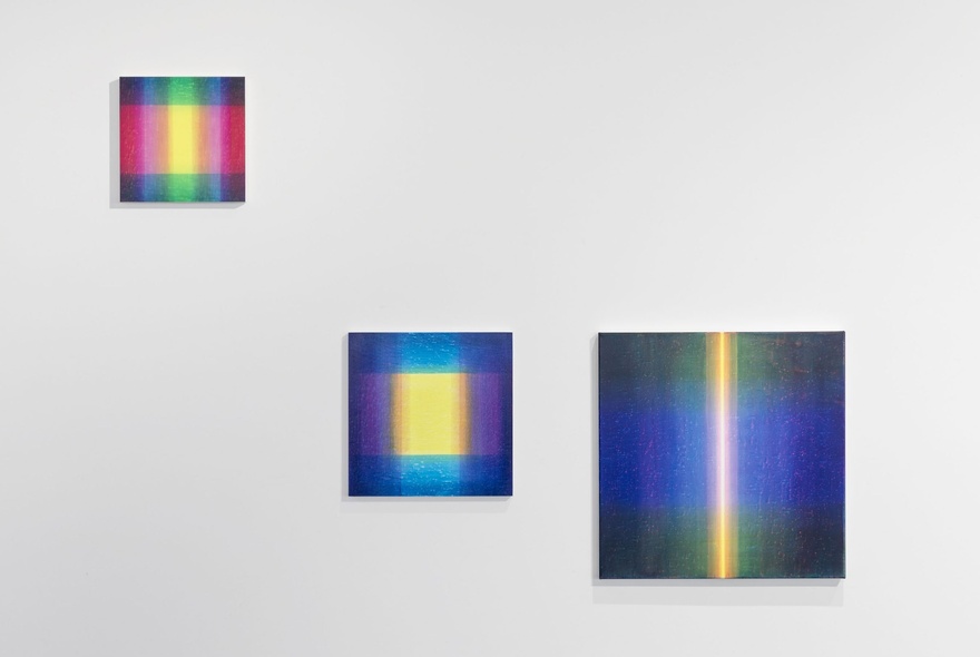 A gallery wall displaying three paintings with block colours and a central light yellow theme. 