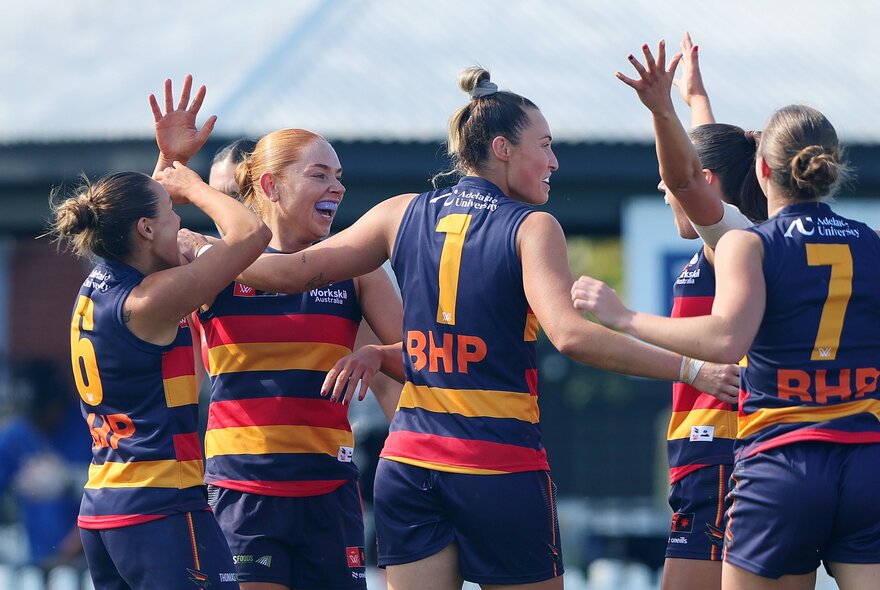 Five Adelaide AFLW players celebrating on the field giving each other high-fives. 
