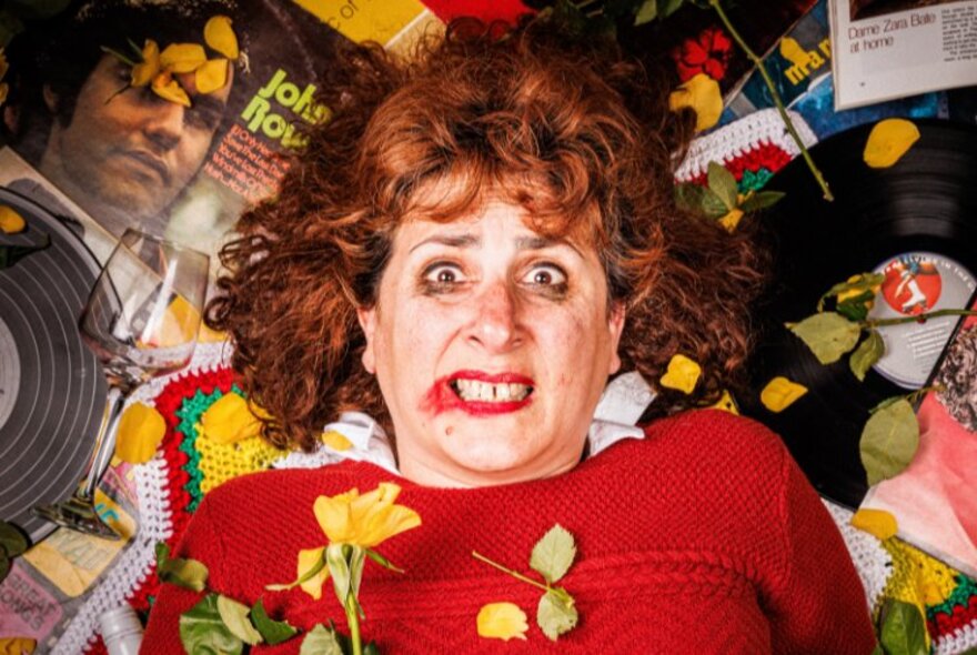 A woman laying in a mess on a floor with a terrified look and smudged lipstick and mascara. 