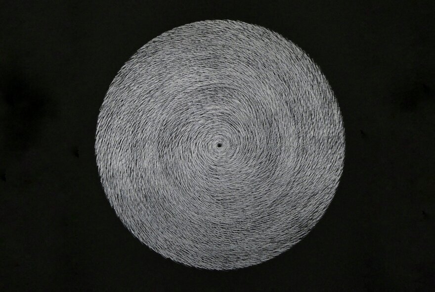 A print showing a central grey circle with grooves like a woven placemat, against a black background. 