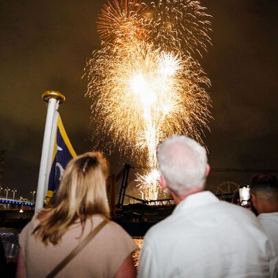 People watching a fireworks display over the City of Melbourne from a boat on the Yarra River. 