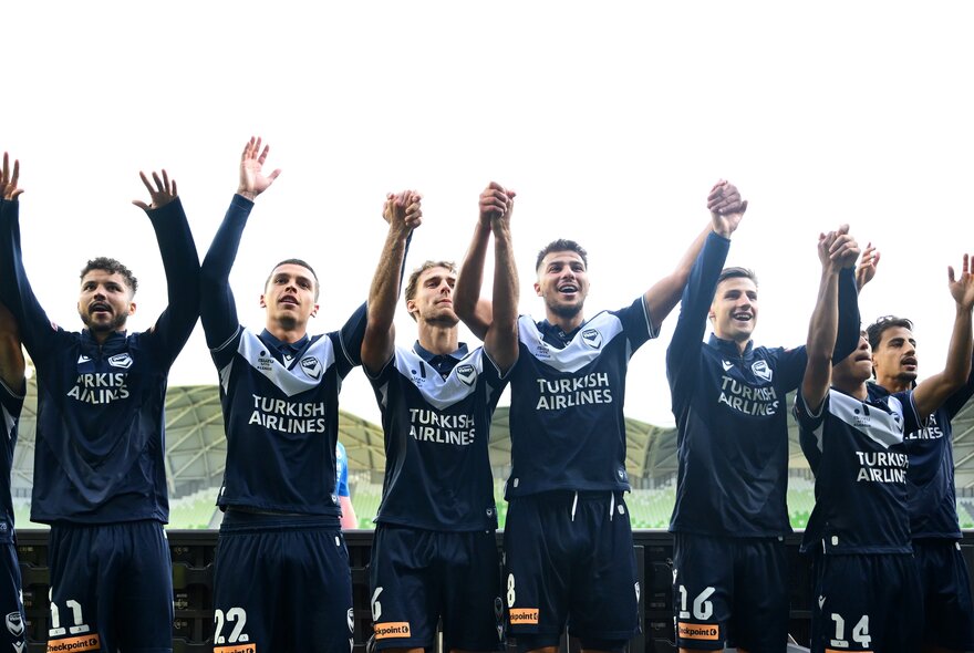 Soccer players with arms outstretched in victory.
