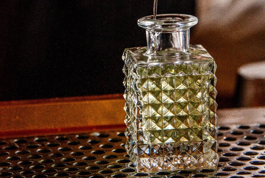 A cut crystal bottle resting on a bar.