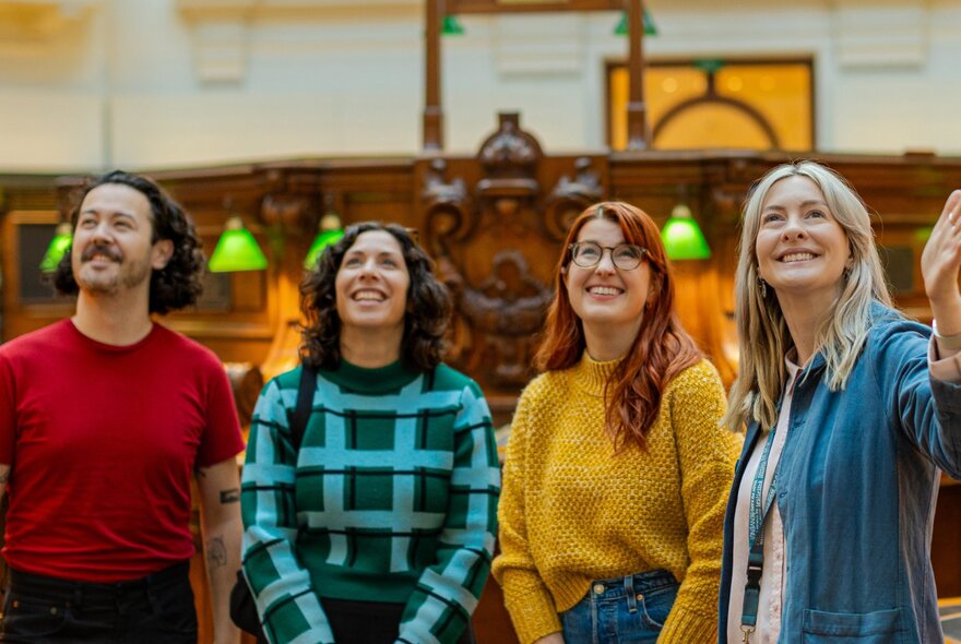 A small tour group looking up from the ground floor of the La Trobe Reading Room.