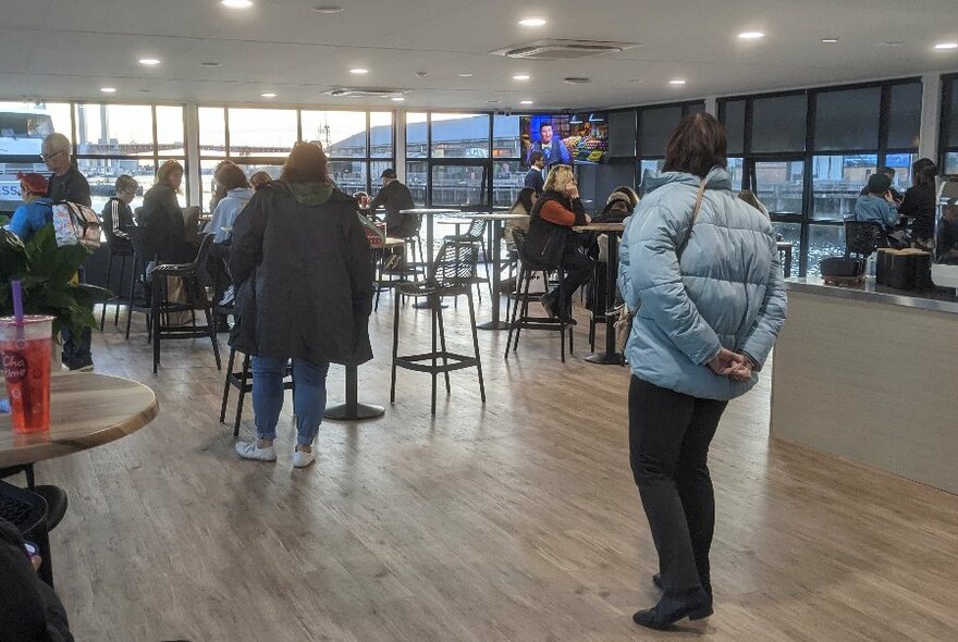 Large open cafe space with stools and tables overlooking harbour.