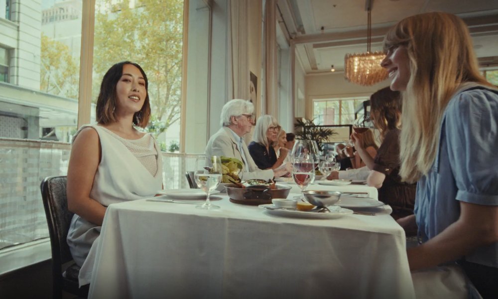Melissa Leong dining with a friend at Gimlet, the table has a white tablecloth, with wine and food plates.