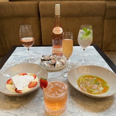 A selection of dishes, cocktails and bottle of rose in a restaurant. 