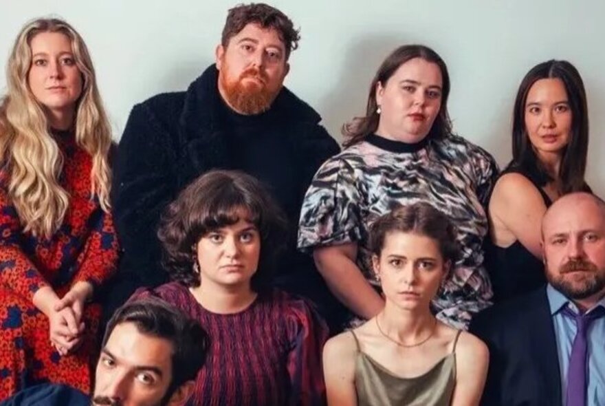 A group of unsmiling people posing together for the camera, a mix of men and women.