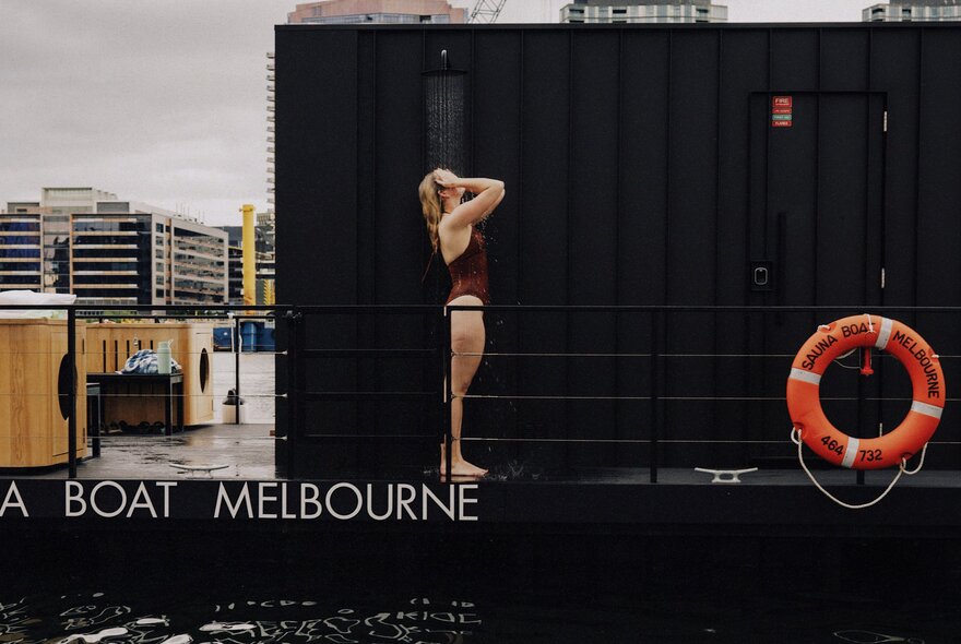 Woman taking an outdoor shower on board a floating barge in Docklands.