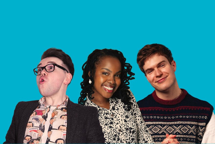 Three young comedians - two men and one woman -  in a group posed against a blue background.