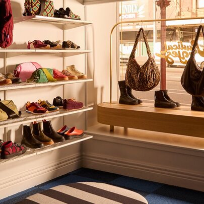 Shop window with shelves of shoes and hanging handbags.