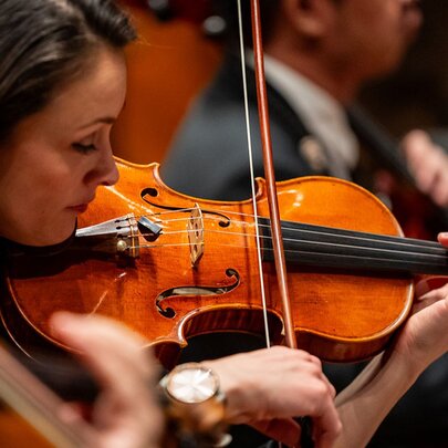 Close shot of a female violinist playing in an orchestra.
