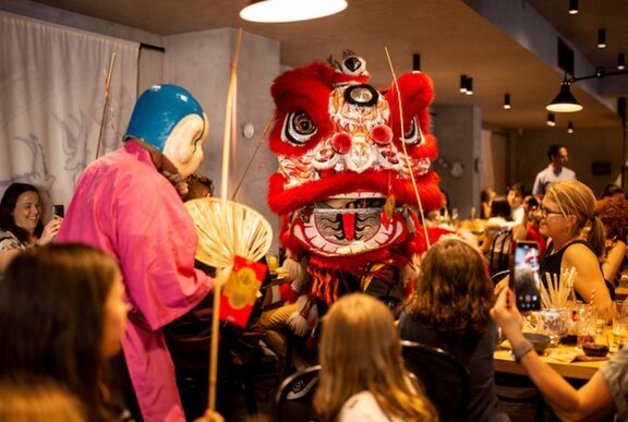 A Chinese dragon in a restaurant with diners looking on. 