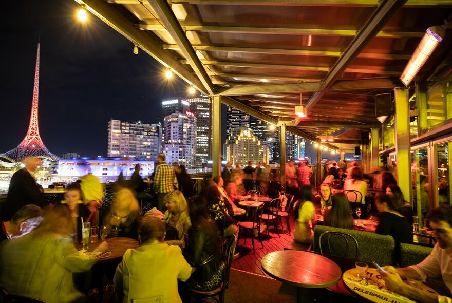 Diners at a rooftop bar at night.