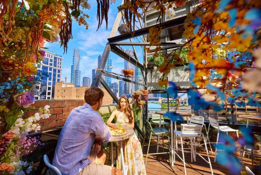 A couple sitting on a rooftop surrounded by plants and greenery