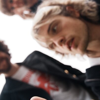 A blurry shot of three members of the band Seven Pound Halo, looking down toward the camera against a bright, overexposed white background.