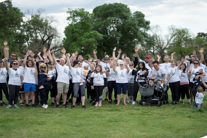 A crowd of runners standing in a group and waving.