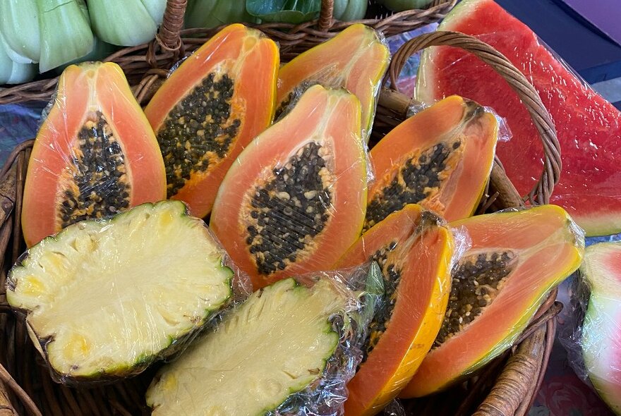 A basket of cut fruit including pineapple and pawpaw.