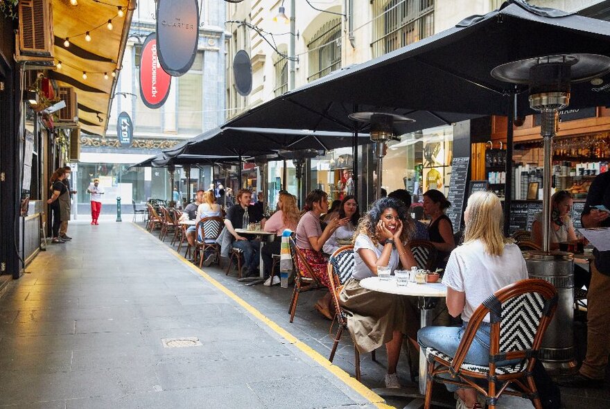 People sitting at outdoor cafe tables in Degraves Street.