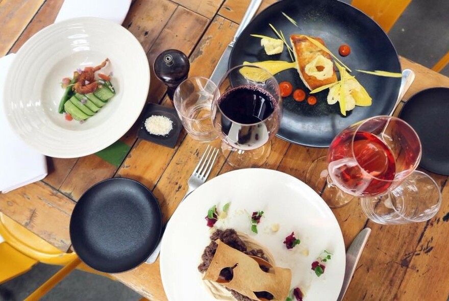 Wooden table with glasses of wine and dishes of food.