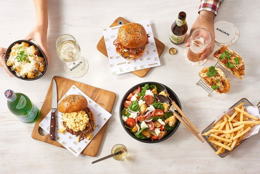 Top down view of a plates of food on a table, plus a glass of wine and beer.