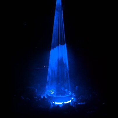 A blue cone spotlight used during a live performance, creating a dramatic effect in a dark environment. 