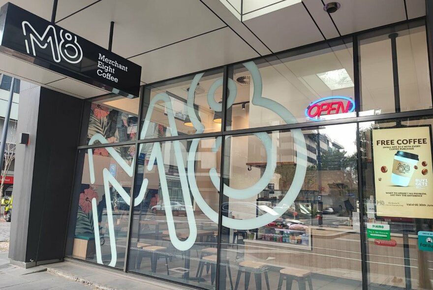 The shopfront windows of Merchant 8 cafe, with black frames and a large 'M8' painted in light blue across the front.