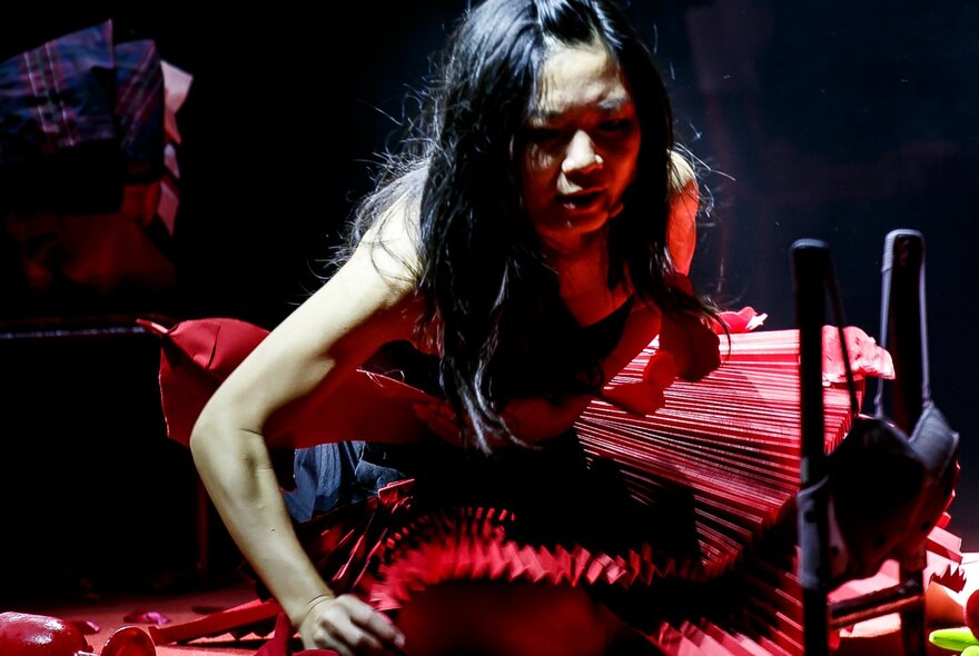 Woman wearing a red dress, squatting on the floor.