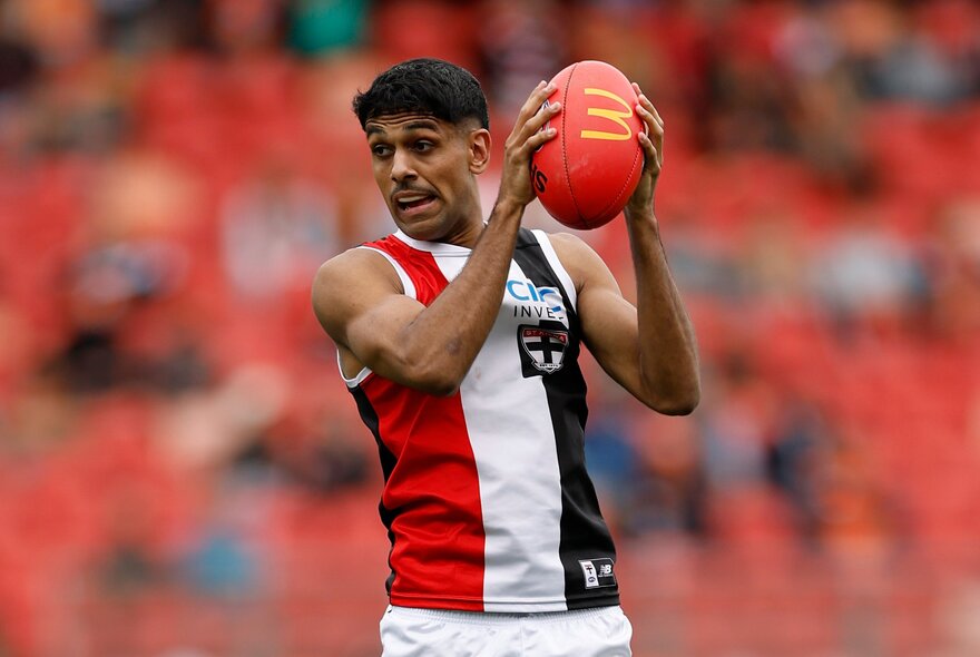 A St Kilda AFL player holding the football in his hands, as if he has just marked it.