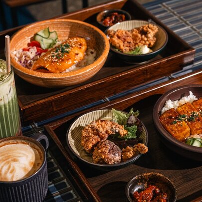 An array of Japanese food in bowls served on trays, with drinks. 