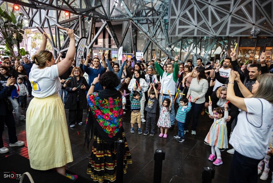 A crowd of people watching Persian traditional dancers at Fed Square in Melbourne.