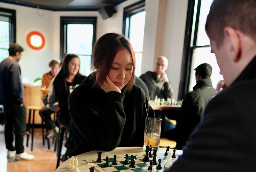 A social chess gathering where people are playing chess matches in an indoor setting of a bar.