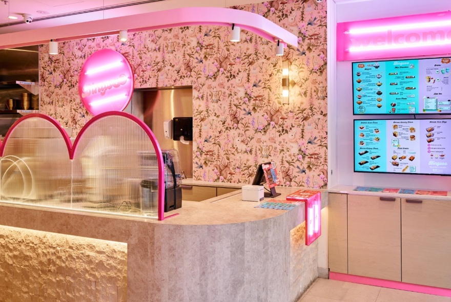 The interior of Bingsoo, Korean Dessert bar, with pink neon lights and television screens showcasing the menu.