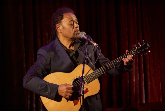 Man playing guitar and singing into a microphone.