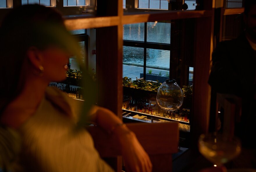 A blurred figure in the foreground, with a bar in the background downstairs.