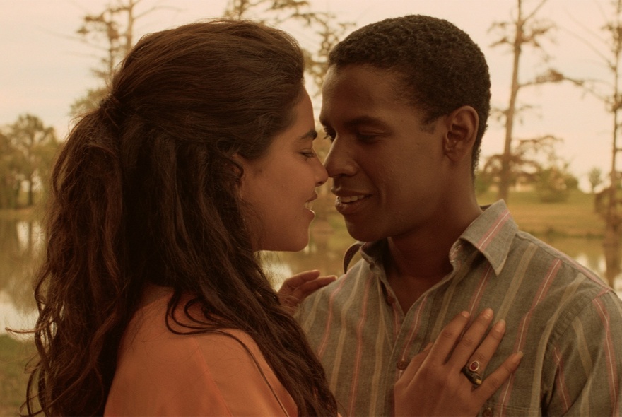 Actors sharing a tender moment with trees in the background.