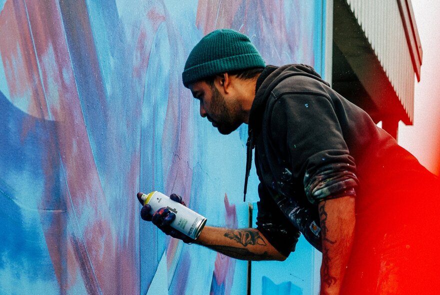 Artist Sahil Roy painting a mural in blue tones. 