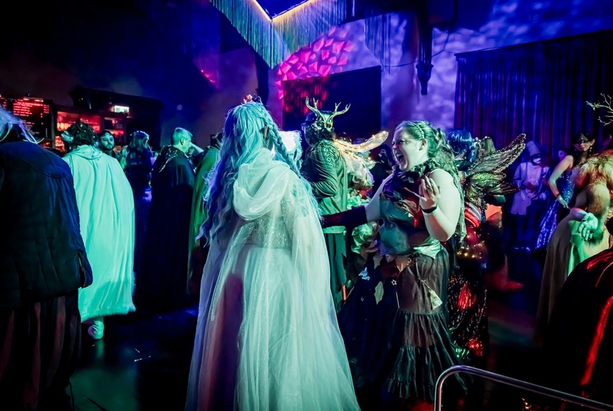 A room of people in fancy dress with dim blue lights. 