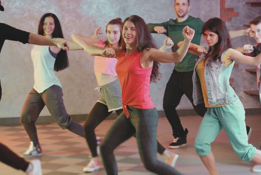 A Latin dance class performing exercise routines in a mixed group.