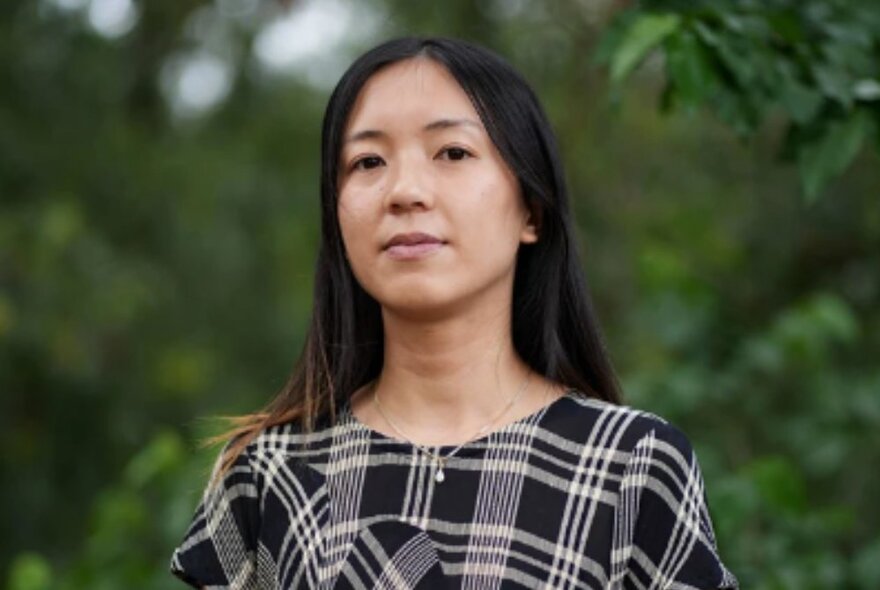 Woman wearing monotone tartan dress in a garden.