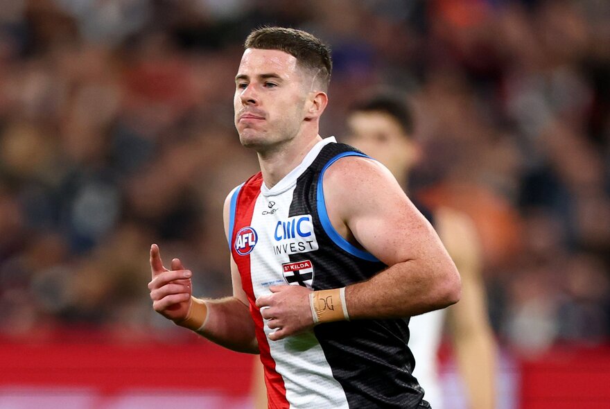 A St Kilda AFL player jogging on the field during a match. 