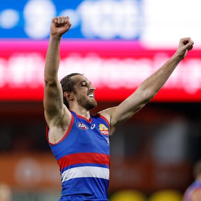 Marcus Bontempelli from the Western Bulldogs cheering with pumped fists raised in the air, on the footy field.