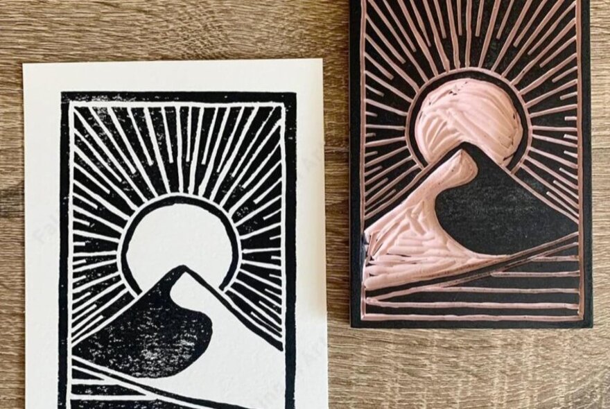 A linocut stamp of a mountain and sun and the printed result.