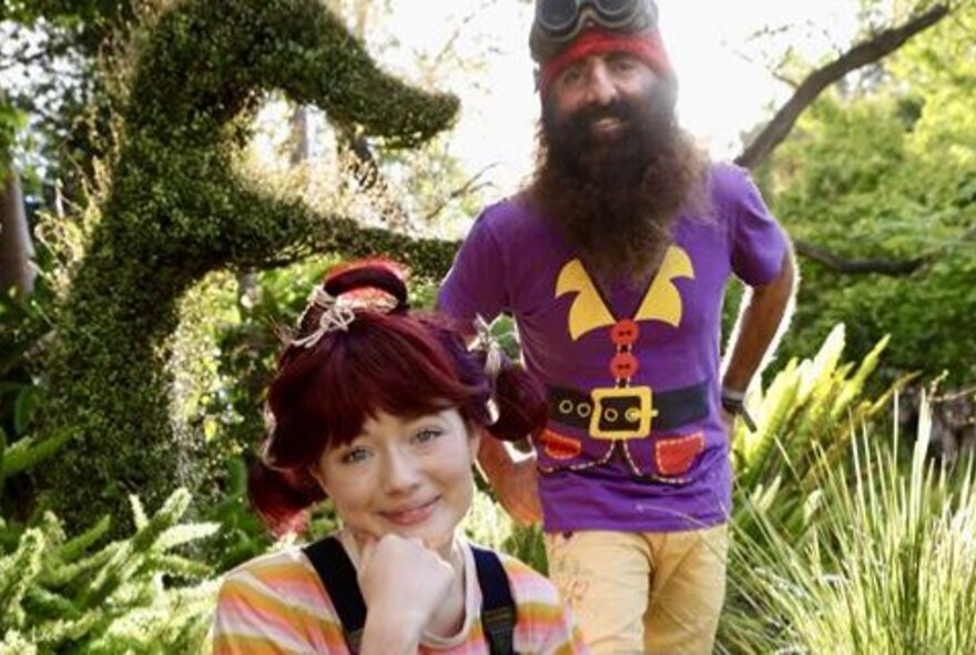 Costa the garden gnome and dirtgirl, posed in a garden, hosts for the Great Big Toy Swap.