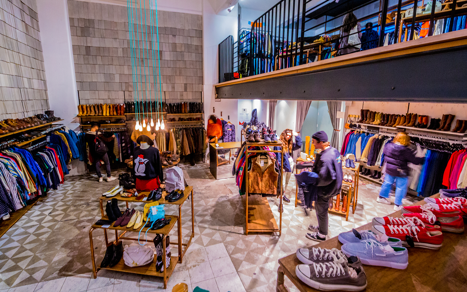 A man browsing a two-storey vintage shop with Converse shoes and jackets.