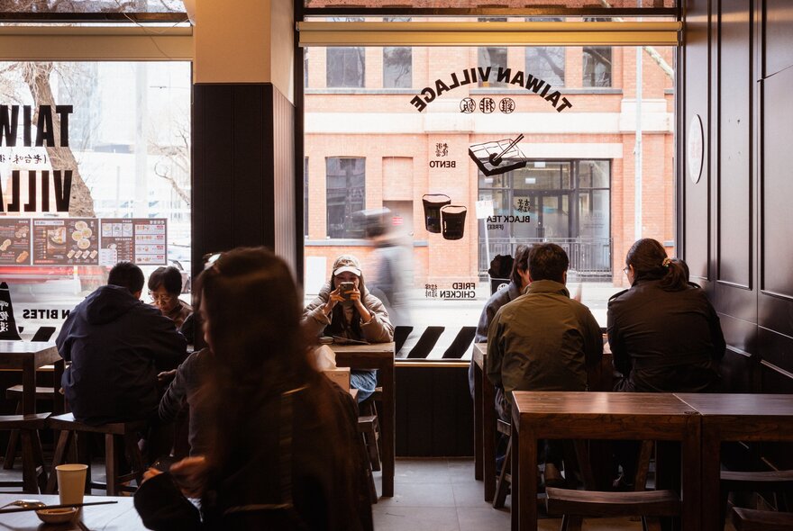 Diners silhouetted against front windows in a city cafe.