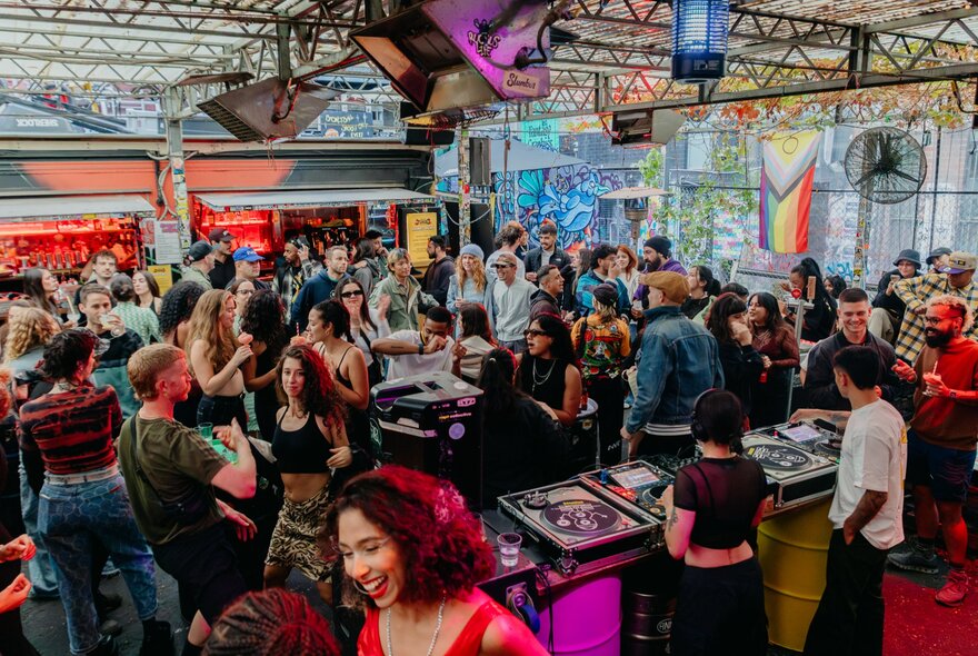 Crowded indoor drinking venue with DJs.