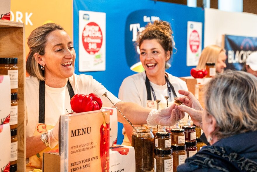 An attendee at The Little Food Market at the Royal Exhibition Building, interacting with a smiling stall holder and being handed some food to sample.