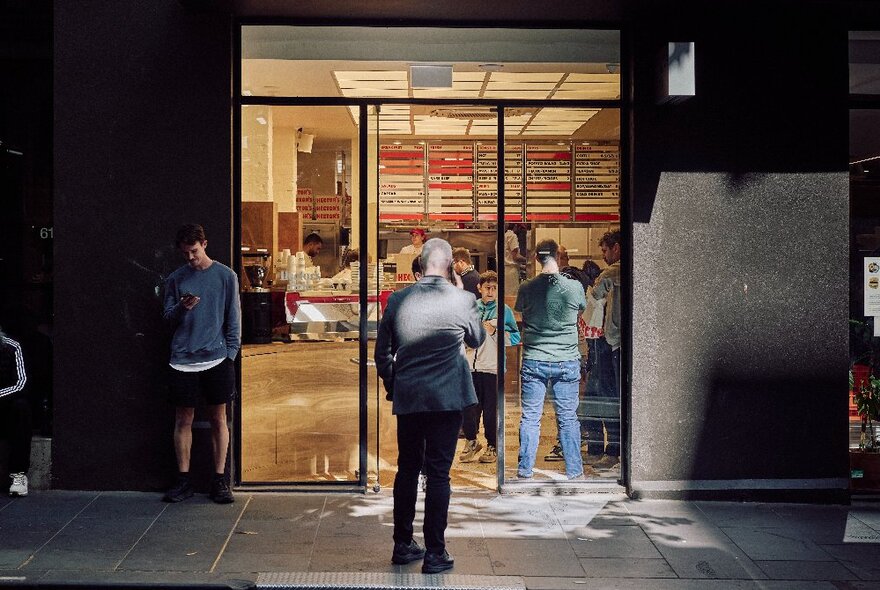 People lined up outside the large glass doors of Hector's Deli on Little Collins Street in Melbourne.